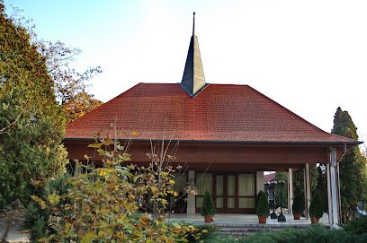 Temető búcsúzóterem: fákkal körülvett, vörös cseréptetős épület.