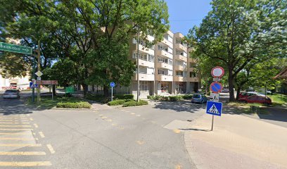 Utcakép, jelzőtáblákkal és fákkal, temetkezési szolgáltató közelében.