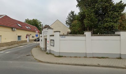 Temető bejárat, fehér fal, zöld növényzet.