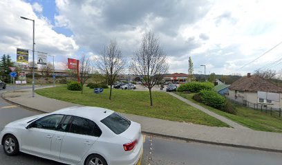 Közlekedési kép, parkoló és épületek láthatók.