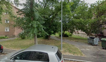 Zöld terület lakóépületek mellett, temető közelében.
